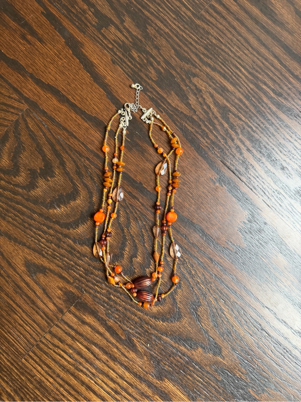 Multi-strand necklace featuring layers of orange and faceted brown beads